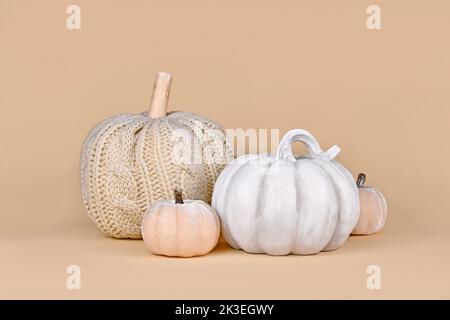 Herbstdeko mit gestricktem beigen Kürbis und grauem Steinkürbis im Boho-Stil Stockfoto