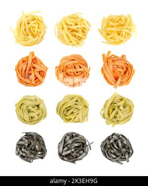 Bunte Tagliatelle Pasta, von oben in Nester verdreht, isoliert über Weiß. Vier Reihen ungekochter, getrockneter traditioneller italienischer Eiernudeln. Stockfoto