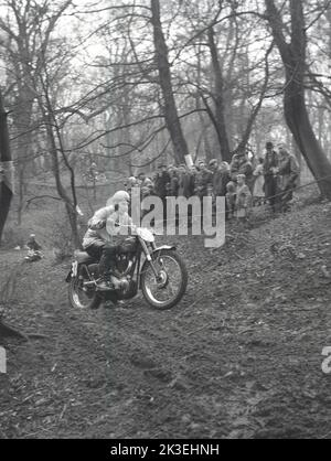 1954, historisch, draußen auf unwegsamem Gelände in einem Wald, Zuschauer beobachten einen Konkurrenten, der ein Motorrad der Ära, ein Ariel, in einem Gerangel oder Proberennen in Seacroft, Leeds, England, Großbritannien, organisiert vom West Leeds Motor Club, fährt. Stockfoto