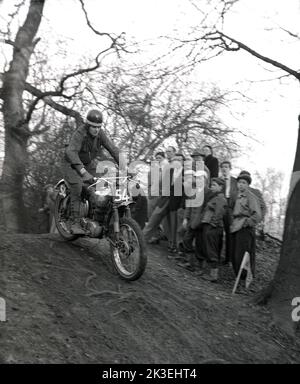 1954, historisch, draußen auf steilem, unwegsamem Gelände in einem Wald, Zuschauer beobachten einen Konkurrenten, der ein Motorrad der Zeit fährt, bei einem Gerangel- oder Testrennen in Seacroft, Leeds, England, Großbritannien, organisiert vom West Leeds Motor Club. Stockfoto