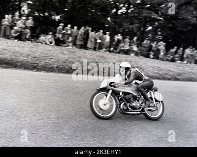 1954, historisch, Zuschauer beobachten einen Motorradfahrer auf dem Platz bei den Scarborough-Rennen, England, Großbritannien. Die berühmte Oliver’s Mount Road Rennstrecke ist Englands einzige natürliche „Road“ Rennstrecke, bekannt als „Mini TT“. Die anspruchsvolle, hügelige Strecke liegt in der Nähe von Scarboroughs Strandpromenade, daher wurden die Rennen traditionell als Scarborough-Rennen bezeichnet. Stockfoto