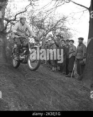 1954, historisch, draußen auf unwegsamem Gelände in einem Wald, Zuschauer beobachten Teilnehmer 38 auf einem Motorrad der Ära, möglich ein Ariel, in einem Gerangel oder Proberennen in Seacroft, Leeds, England, Großbritannien, organisiert vom West Leeds Motor Club. Stockfoto