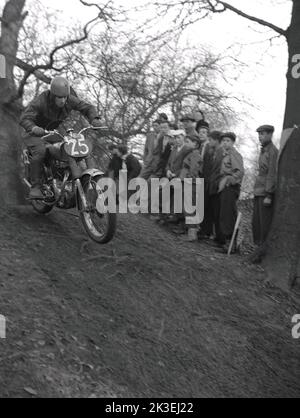 1954, historisch, draußen auf steilem, unwegsamem Gelände in einem Wald, Zuschauer beobachten einen Konkurrenten, der ein Motorrad der Zeit fährt, bei einem Gerangel- oder Testrennen in Seacroft, Leeds, England, Großbritannien, organisiert vom West Leeds Motor Club. Stockfoto