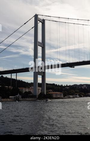 Blick auf eine Yacht, die auf dem Bosporus und der Brücke in Istanbul vorbeifährt. Es ist ein sonniger Sommertag. Wunderschöne Szene. Stockfoto