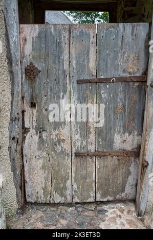Sehr alte verwitterte Holztür mit verrosteten Metallarbeiten Stockfoto