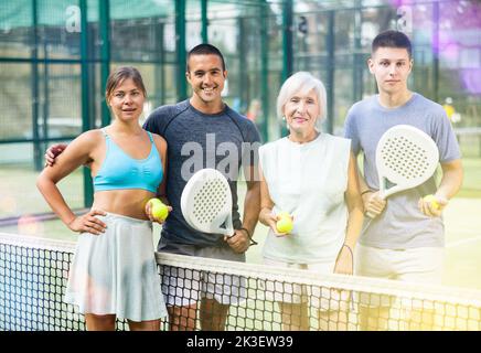 Porträt von vier glücklichen Padel-Spielern auf dem Tennisplatz im Freien Stockfoto