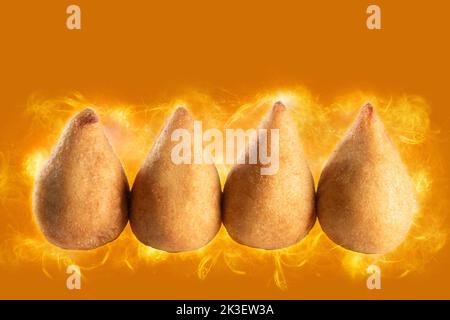 Coxinha. Traditioneller brasilianischer Snack. Orangefarbener Hintergrund. Hähnchendrumstick. Stockfoto