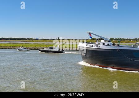 Rotterdan, Niederlande - August 2022: Großer Industriekahn wird zwei kleine Motorboote passieren Stockfoto