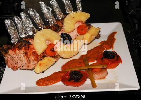 Schweinekotelett gekocht und auf einem Teller mit einer Tomaten- und Zwiebelgarnitur serviert Stockfoto