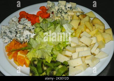 Teller mit Salat aus Gemüse, Obst und Käse. Stockfoto