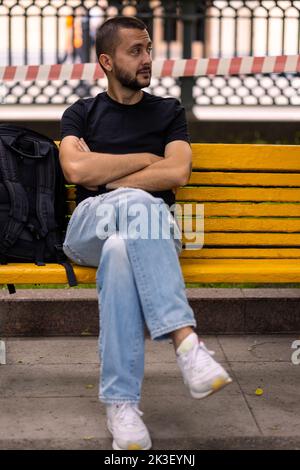 Kaukasischer Mann sitzt auf einer Bank Stockfoto
