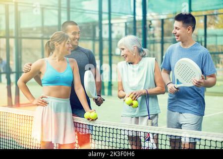 Glückliche Spieler mit Schlägern für Padel, die auf dem Tennisplatz im Freien reden Stockfoto