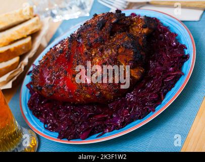 Gebratene Schweinshaxe mit geschmortem Kohl Stockfoto