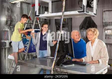 Großeltern und Enkelkinder, die sich im Fluchtzimmer mit einem Konundrommel herumtoben Stockfoto