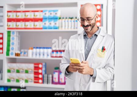 Junger hispanic-Mann Apotheker mit Smartphone in der Apotheke stehen Stockfoto