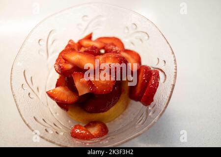 Eine Schüssel mit frisch geschnittenen Erdbeeren auf einem Biskuitkuchen. Erdbeer-Shortcake. USA. Stockfoto