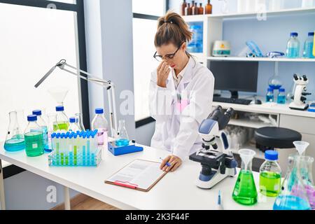 Junge Frau in Wissenschaftleruniform stresste die Arbeit im Labor Stockfoto