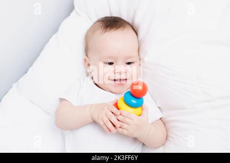 Ein Kind mit einer hölzernen Pyramide. Frohes Baby. Kinderspielzeug. Holzspielzeug Stockfoto