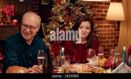 Die wunderschöne Frau zu Hause genießt das Weihnachtsessen mit ihren Lieben und lächelt herzlich vor der Kamera. Festliche fröhliche Menschen feiern Winterurlaub mit traditionellen hausgemachten Speisen. Stockfoto