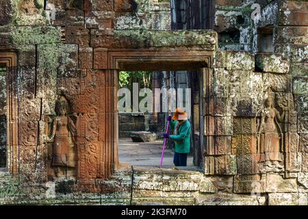 Kambodscha. Provinz Siem Reap. Der archäologische Park von Angkor. Eine Frau reinigt die alten Ruinen des Banteay Kdei Tempels Stockfoto