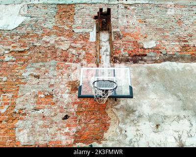 Altes und abgenutztes Outdoor-Basketballnetz auf dem Hintergrund der roten Backsteinmauer, urbaner Spielplatz, Innenstadt in der Stadt Stockfoto