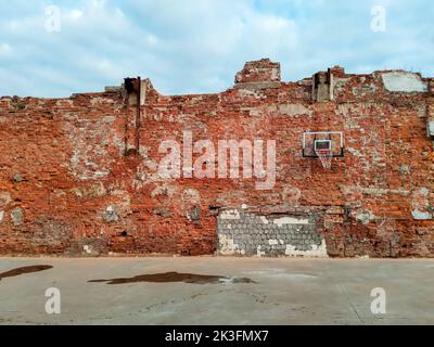 Altes und abgenutztes Outdoor-Basketballnetz auf dem Hintergrund der roten Backsteinmauer, urbaner Spielplatz, Innenstadt in der Stadt Stockfoto