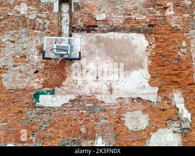 Altes und abgenutztes Outdoor-Basketballnetz auf dem Hintergrund der roten Backsteinmauer, urbaner Spielplatz, Innenstadt in der Stadt Stockfoto