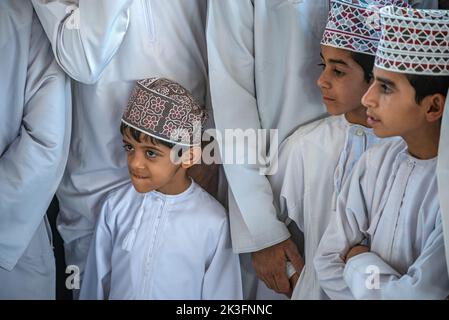 Drei Jungen mit kuma (traditioneller Rundhut omanis) auf dem freitagmorgen Viehmarkt in Nizwa, Oman Stockfoto