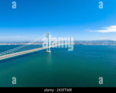 Lange Hängebrücke über ruhiges Wasser am sonnigen blauen Himmel Stockfoto