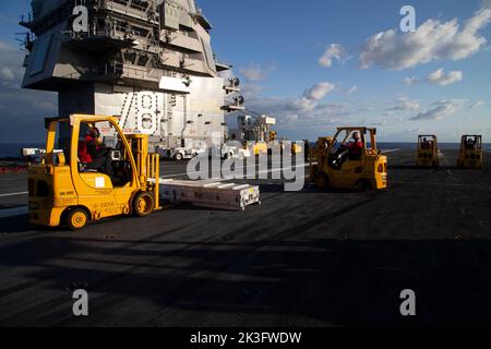 Matrosen, die dem erstklassigen Flugzeugträger USS Gerald R. Ford (CVN 78) zugewiesen wurden, transportieren während einer Munitionsaufladung am 25. September 2022 auf dem Flugdeck die Munitionsabteilung. Ford führt derzeit im Atlantischen Ozean Qualifizierungen von Fluggesellschaften durch und arbeitet für einen geplanten Einsatz im Herbst. (USA Navy Foto von Mass Communication Specialist 1. Class William Spears) Stockfoto