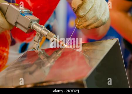 Schweißer Hände mit einem tragbaren Laserschweißgerät - Nahaufnahme Stockfoto