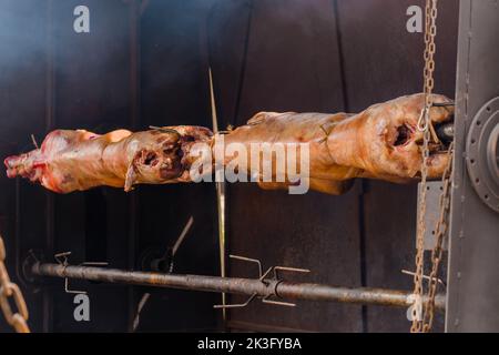 Prozess des Kochens von Widderkadavern am Spieß auf dem sommerlichen Lebensmittelmarkt: Nahaufnahme Stockfoto