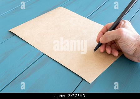 Hand des Mannes mit Füllfederhalter, auf braunem Papier, bereit zu unterschreiben. Stockfoto