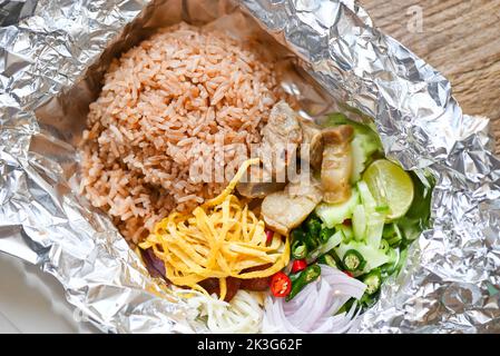 Thai-Lebensmittel auf Box mit Aluminiumfolie Lebensmittelverpackung Essen zum Mitnehmen - Reis gemischt mit Garnelenpaste gebratener Reis auf Box, Reis gewürzt mit Garnelenpaste Rezept, r Stockfoto