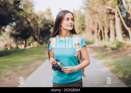 Junge kreative Tourist Mädchen, die Fotos mit einer Vintage-Filmkamera, während Sie im Park zu Fuß. Stockfoto