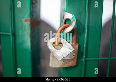 Das Schloss hängt am Tor auf der Straße. Geschlossene Tür. Schutz von Privateigentum. Die Türverriegelung ist verriegelt. Stockfoto