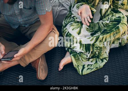 Ein Mann und eine Frau sitzen auf einer Chaiselongue im Park. Vorderansicht. Stockfoto