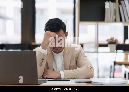 Eine betonte asiatische Geschäftsfrau analysiert die Finanzcharts. Account- und Audit-Konzept Stockfoto