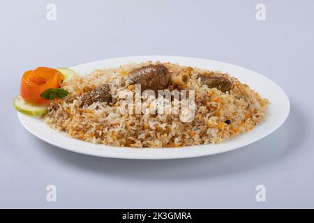 Motton dhum biriyani mit Jeera-Reis und Gewürzen in irdenen Geschirr mit Raitha und Zitroneneingelegter auf grauem Hintergrund angeordnet Stockfoto