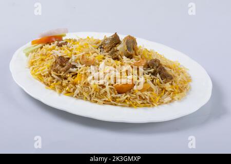 Motton dhum biriyani mit Jeera-Reis und Gewürzen in irdenen Geschirr mit Raitha und Zitroneneingelegter auf grauem Hintergrund angeordnet Stockfoto