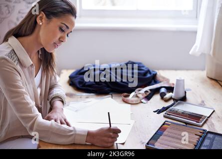 Die Entwicklung der Trends dieser Saison. Eine junge Modedesignerin, die in ihrem Büro Skizzen macht. Stockfoto