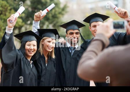 Sagen Sie, dass ich graduiert habe. Eine Gruppe von Freunden posiert für ein Foto in ihren Togas. Stockfoto