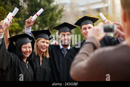 Ihre Erfolge mit Freunden und Familie teilen. Eine Gruppe von Freunden posiert für ein Foto in ihren Togas. Stockfoto