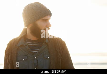 Er ruft den Strand, nach Hause. Ein bärtiger Mann steht am Strand. Stockfoto