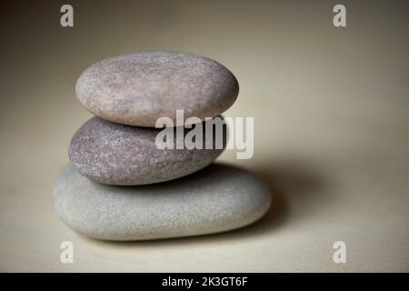 Sich ausbalanciert fühlen. Drei Steine übereinander bei natürlichem Licht ausbalanciert. Stockfoto