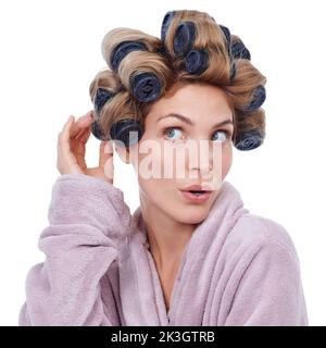 Wie lockig wird es sein. Studioaufnahme einer jungen Frau in Haarwalzen und einer Robe. Stockfoto