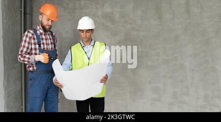 Architekten und Bauingenieure oder Vermessungsingenieure besprechen Pläne und Pläne. Zwei Mann tragen Harthüte und stehen auf dem Baugesit Stockfoto