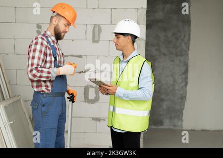 Arbeiter, Inspektor oder Ingenieur mit Baumeister ist Qualitätsprüfung Audit und inspizieren das Gebäude oder Haus mit Tablet tragen Sicherheit Hardhut. Stockfoto