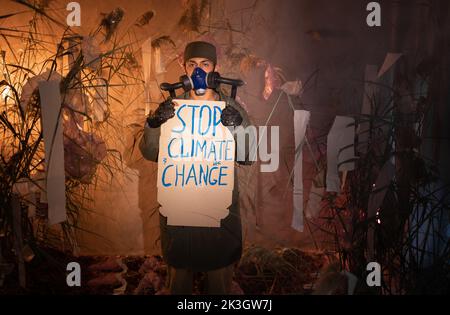 Umweltschutz. Ein Mann in einer Gasmaske hält ein Poster mit dem Wort STOP Climate change in Smoke. Umweltschutz. Luftverschmutzung. Schädlich Stockfoto