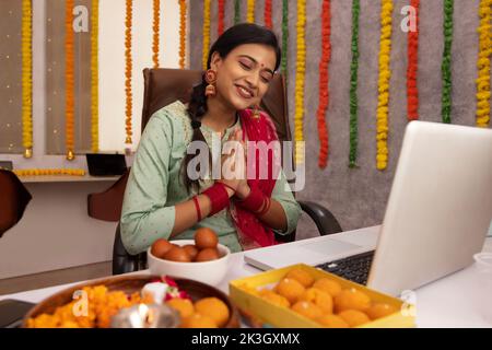 Frau mit Videoanruf auf dem Laptop im Büro während der Diwali-Feier Stockfoto